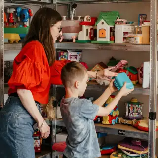 Mother and child browsing pre-owned toys at a second-hand shop